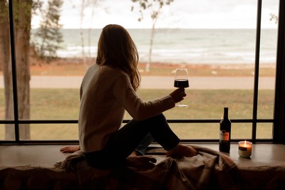 Woman sitting by window drinking a glass of wine 